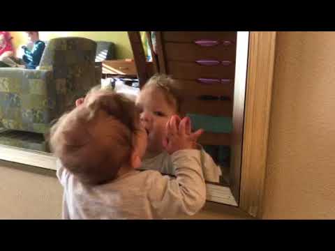 Baby girl talks to herself in the mirror